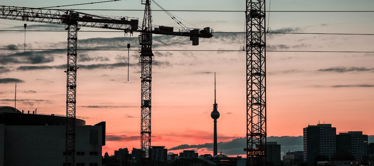 Kräne und Berliner Fernsehturm im Sonnenuntergang